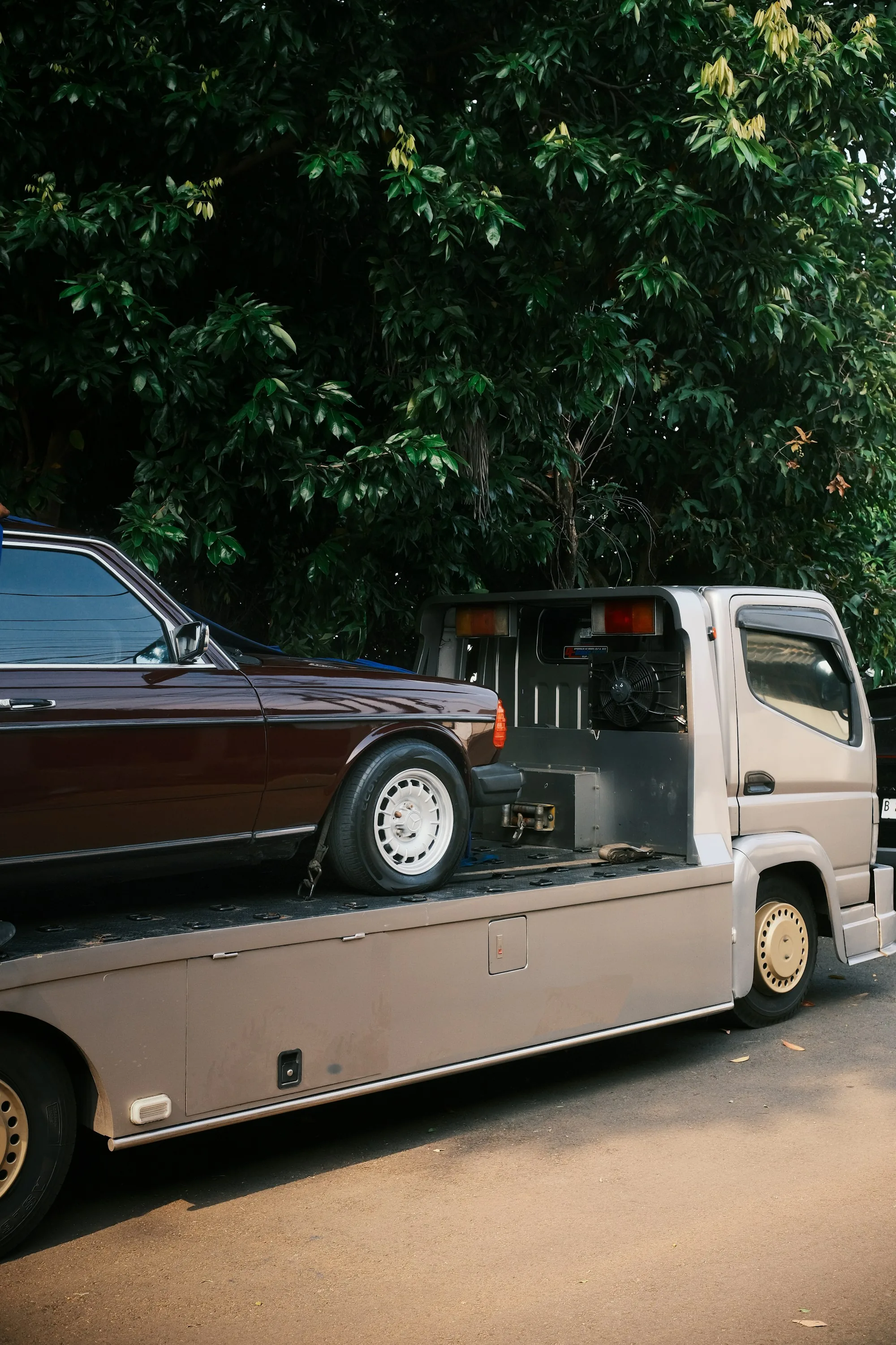 Classic sedan loaded on the deck of a flatbed tow truck